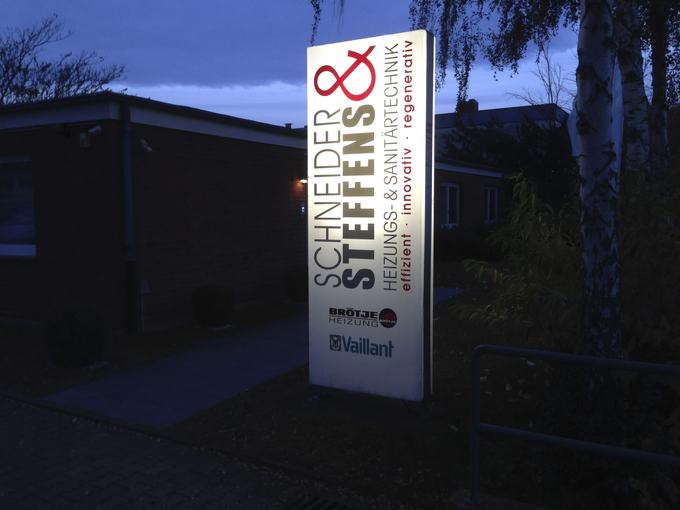 Beleuchteter Werbepylon in der Dämmerung